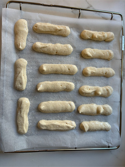Raw ladyfingers generously dusted with powdered sugar before oven