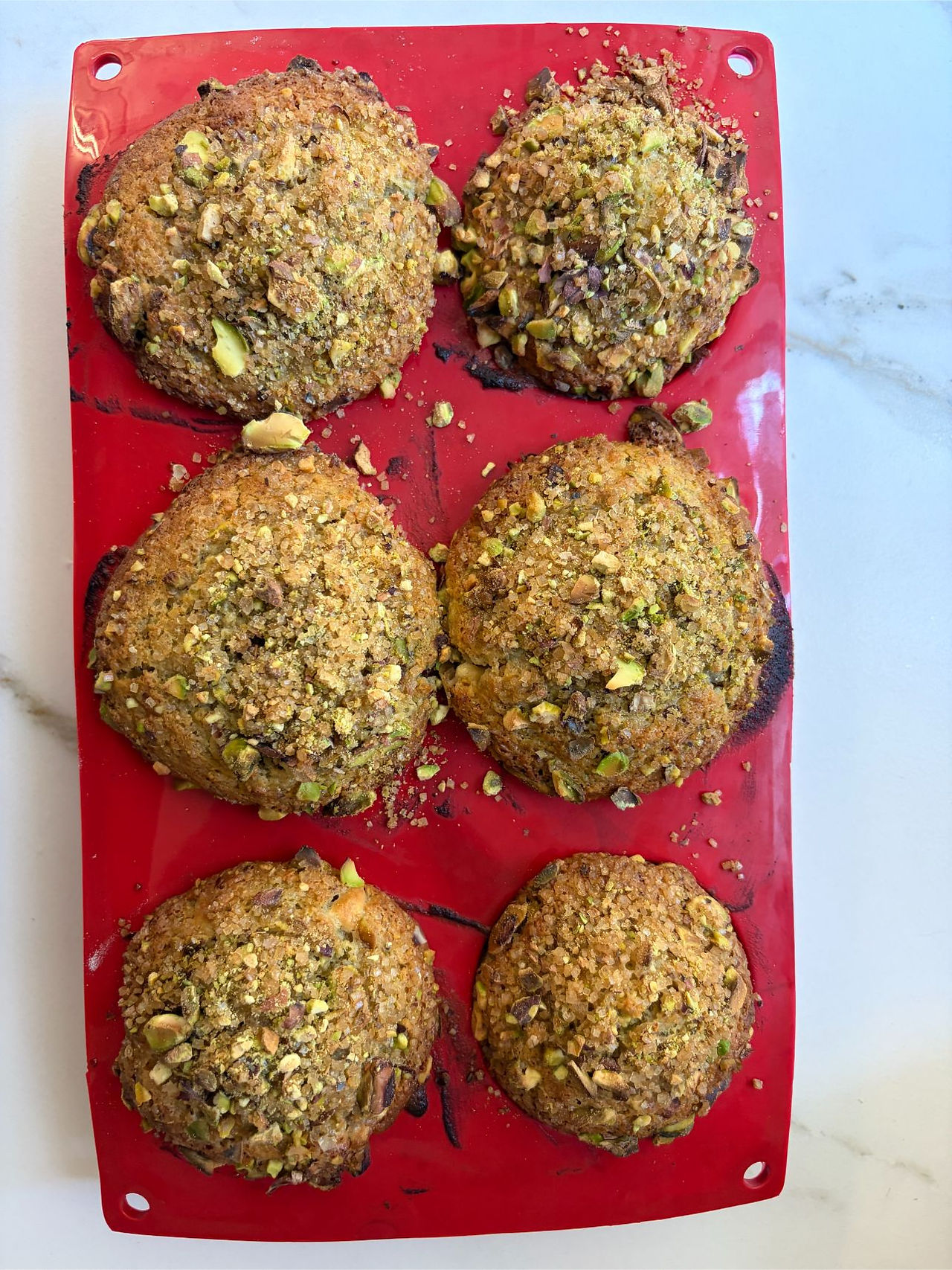 Pistachio white chocolate bakery muffins with perfect high domes crunchy pistachio topping and golden bakery-style finish