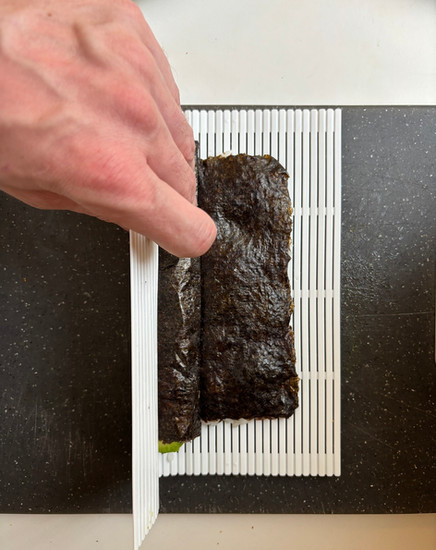Rolling kappa maki sushi tightly with a mat to form a clean cucumber roll