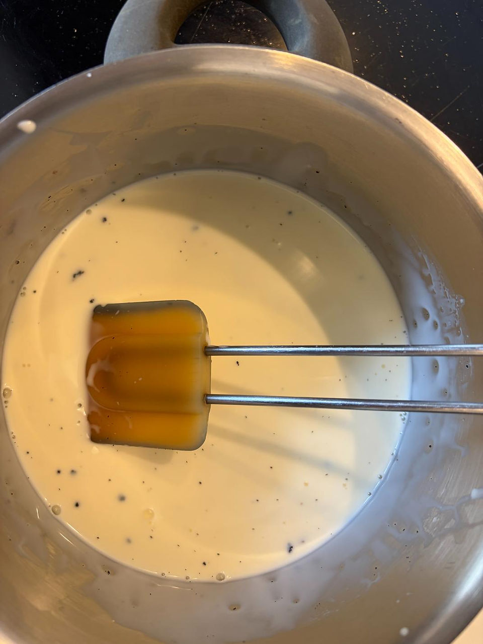 Dissolving gelatin into warm vanilla cream mixture for silky panna cotta texture