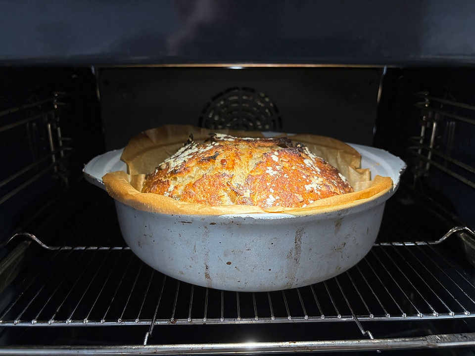 Sourdough bread baking inside a Dutch oven in a home oven