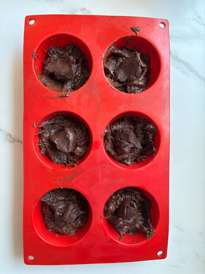 filling the muffin molds with batter and ganache filling