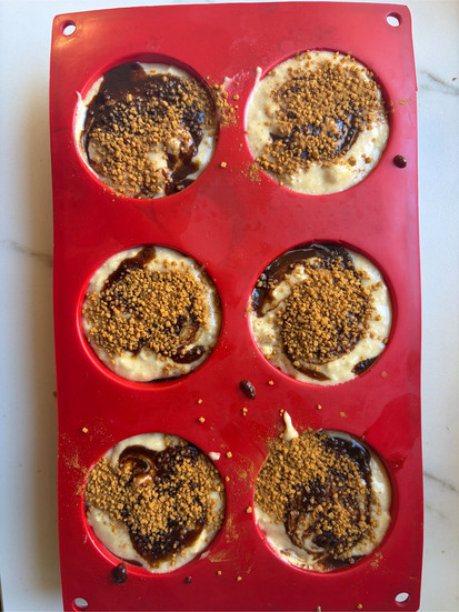 Sprinkling cinnamon sugar topping over muffins for a crunchy bakery-style crust