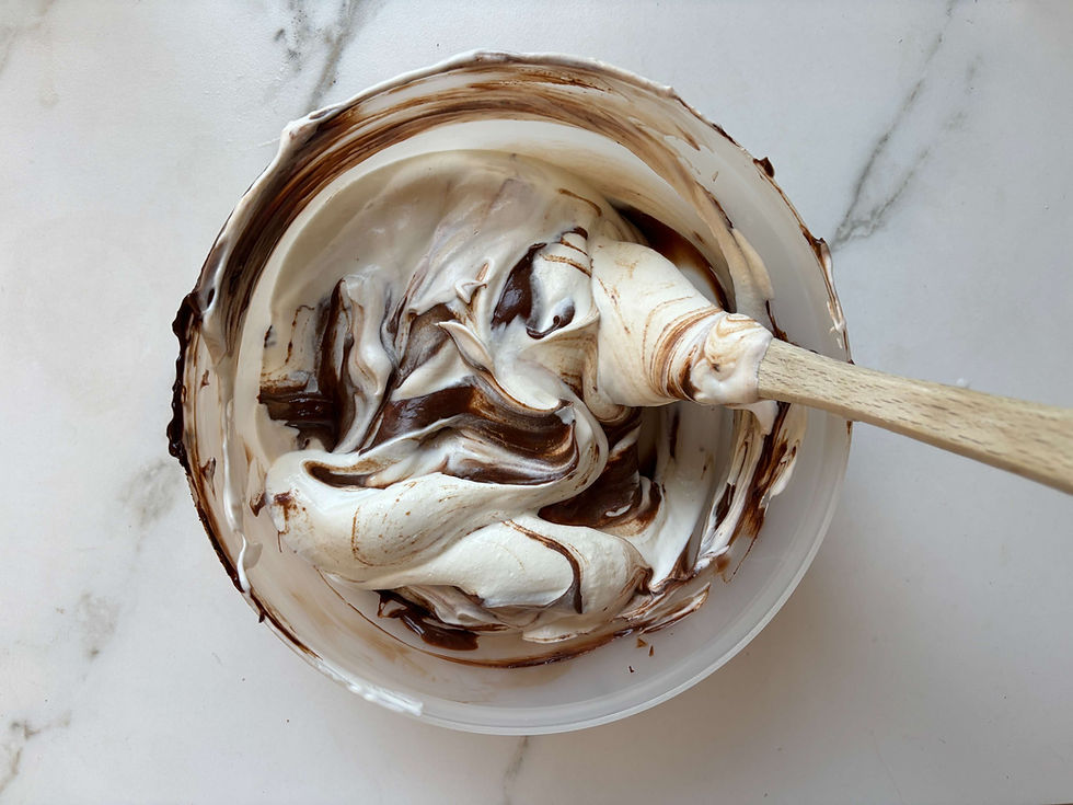 Gently folding melted chocolate into whipped cream for chocolate mousse