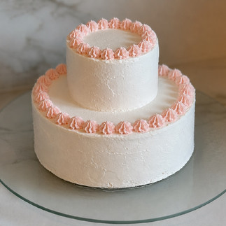 dulce de leche cake decorated with pink whipped cream rosettes on smooth mascarpone frosting