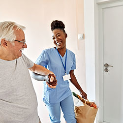 Happy senior man and caregiver entering home with groceries