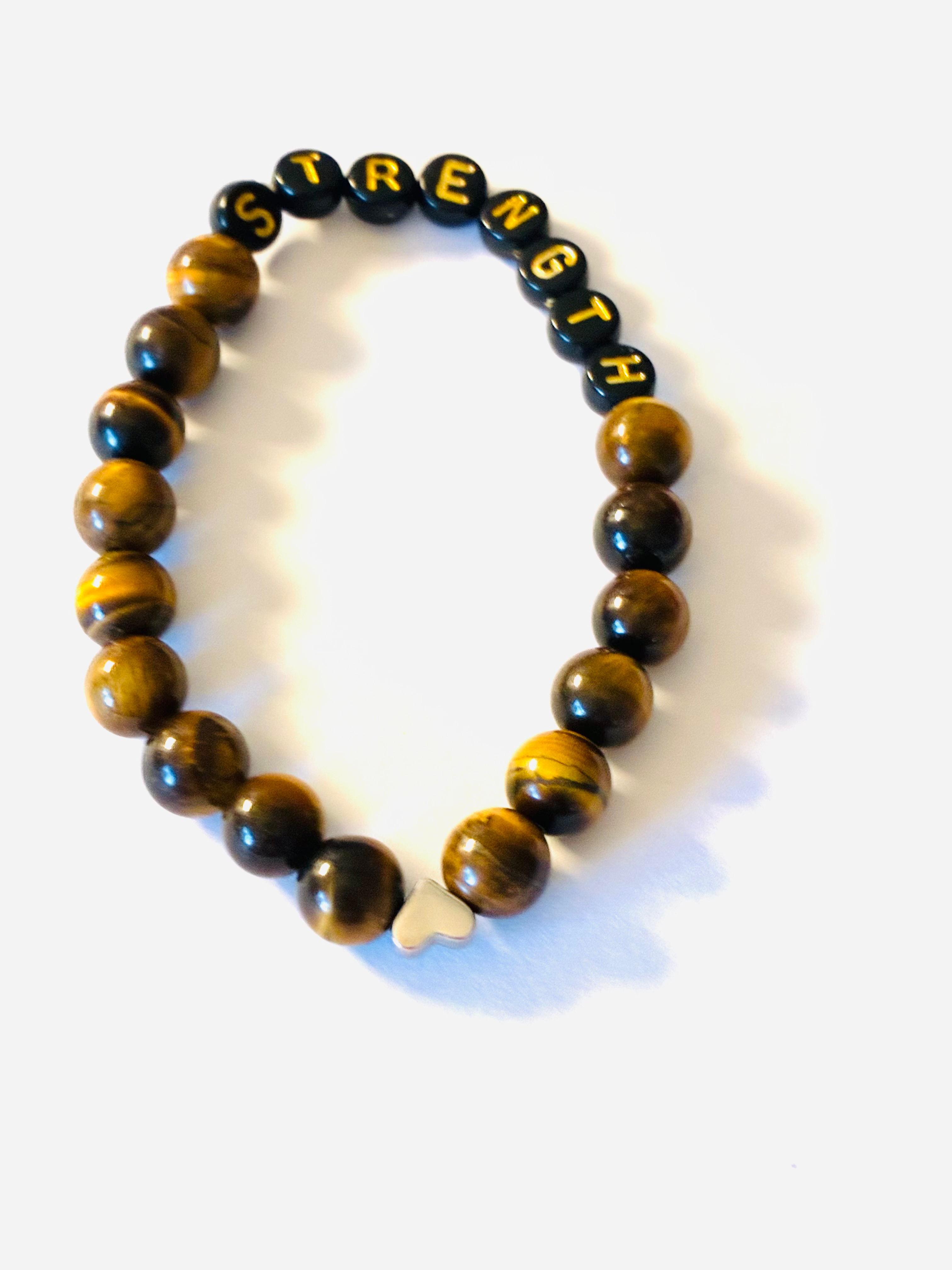 Tiger’s eye stone bracelet with black letter beads spelling STRENGTH and a silver heart charm