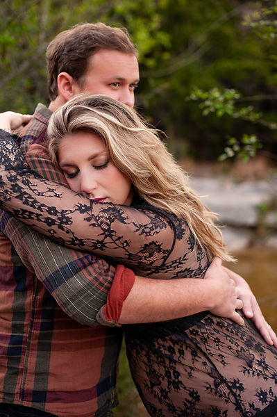 husband embracing wife during unscripted maternity portrait session in a creek near kingsport tennessee