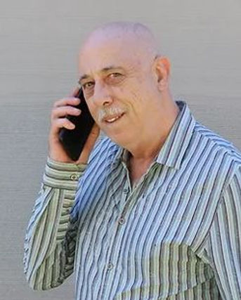 man wearing green striped shirt talks on mobile phone