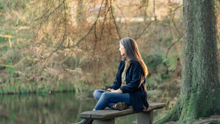 Midlife woman resting outdoors in warm clothing during perimenopause, reflecting on nervous system balance and recovery