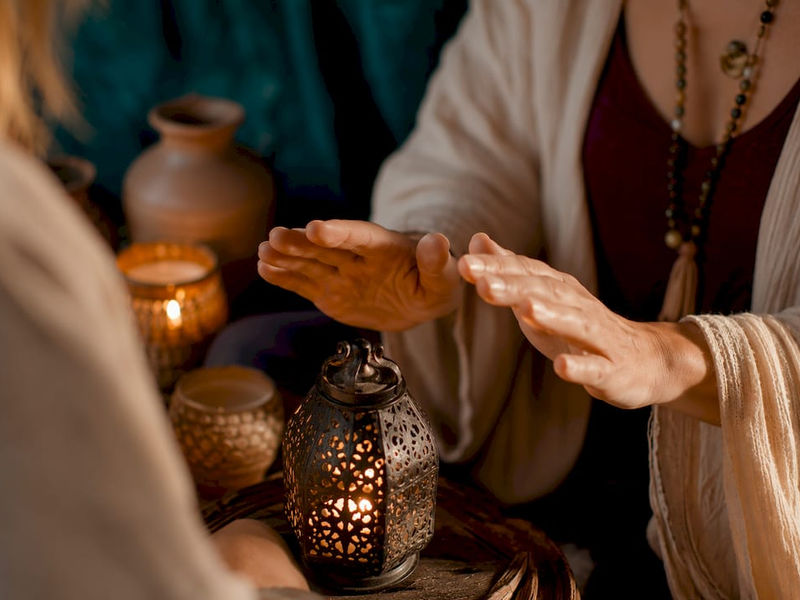 Heilende Hände bei einem Ritual über einer Schale mit Kerzenlicht
