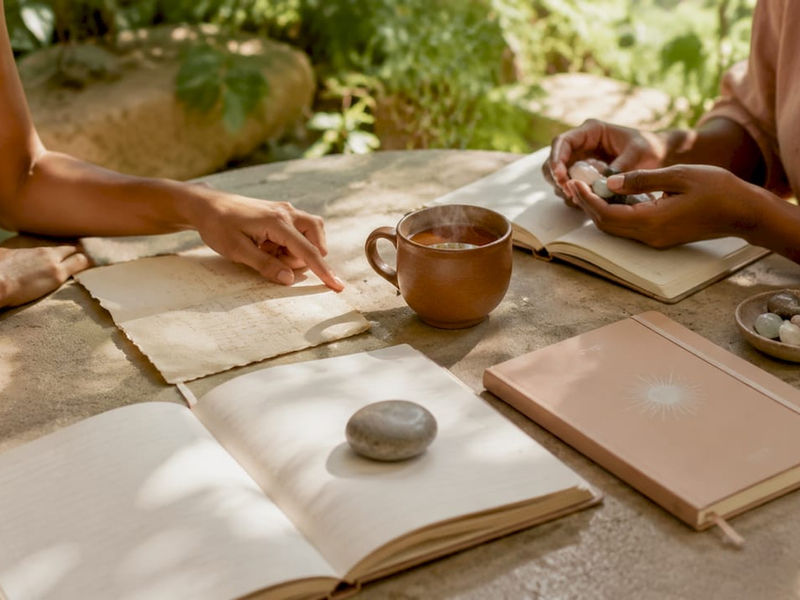 Manos escribiendo notas con libros sobre bienestar