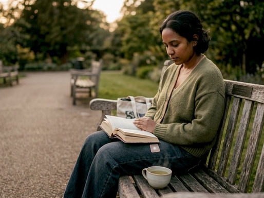 Person quietly reflecting on a park bench in soft light