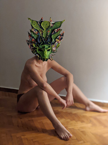 Femme portant un masque de dragon vert assise par terre
