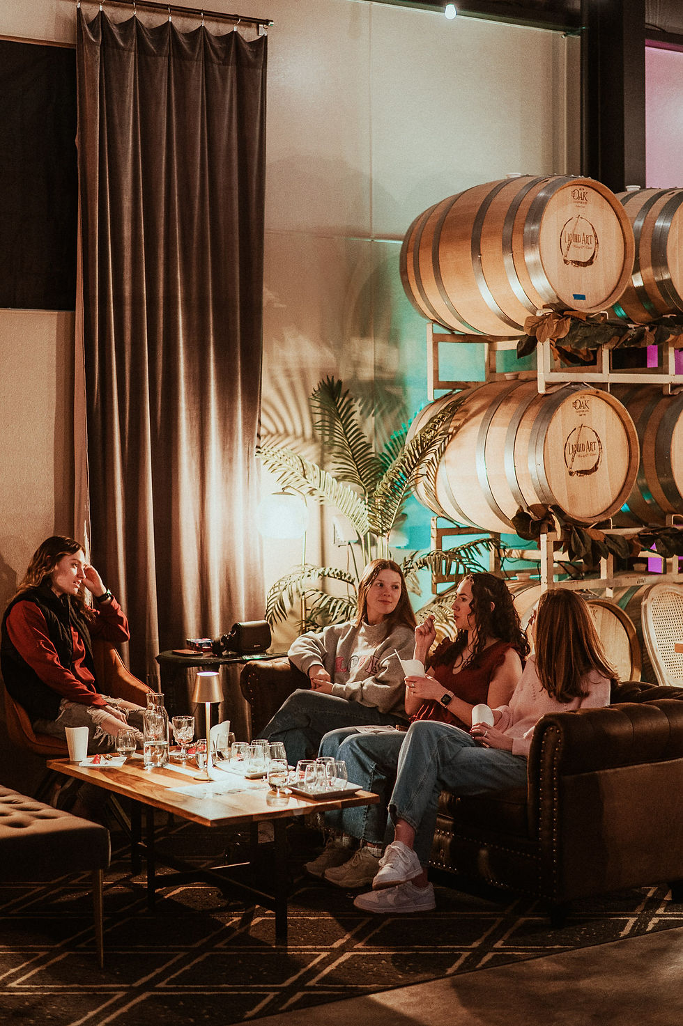 A group of four people sitting on a couch around a table that is filled with wine glasses.