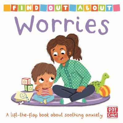 A woman of colour sits on play mat, comforting a small boy of colour. Toys surround them.