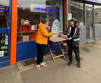 An Opus distributions worker in a black high vis jacket delivering some flyers to a local shop.