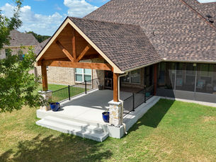 A pergola extension and patio of the back of a house with a brown roof