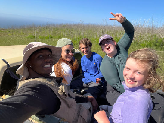Di'Carlo, Caleb, and the rest of their field crew pose in the back of a pick-up truck driving through SCI