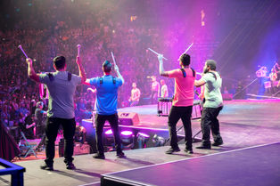 drumming muscians onstage in front of cheering crowd
