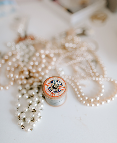 Flatlay of lots of pearl necklaces with a thread spool