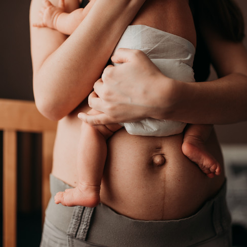 Ventre de femme en post-partum, ventre après-accouchement, jeune maman avec nouveau-né dans les bras