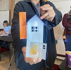 Man holding a paper lantern resembling a house with a cool light inside.