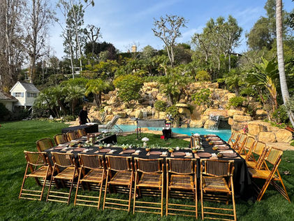 Large backyard hibachi dinner setup with tables and chairs arranged around a pool