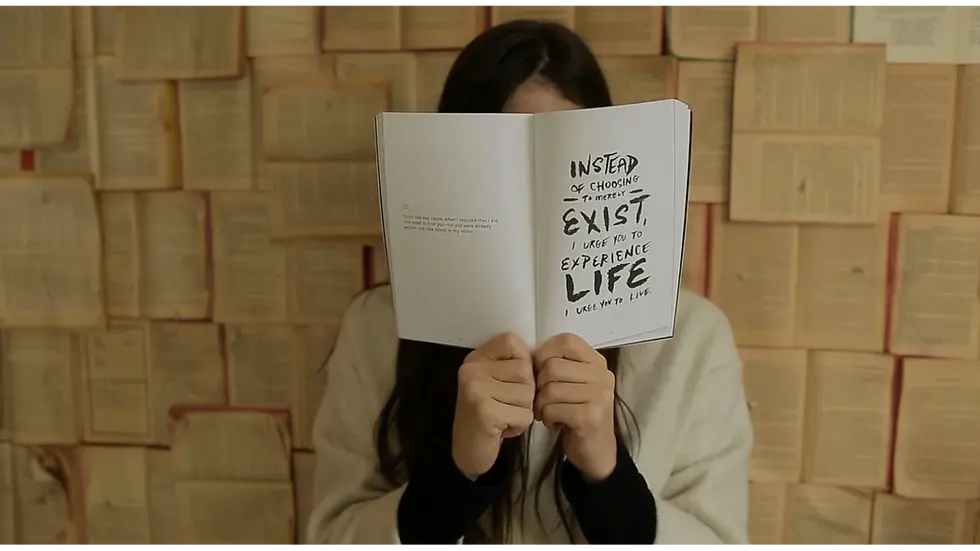 Woman covering her face with a book, reflecting on how small steps to rebuild and reset your life bring clarity