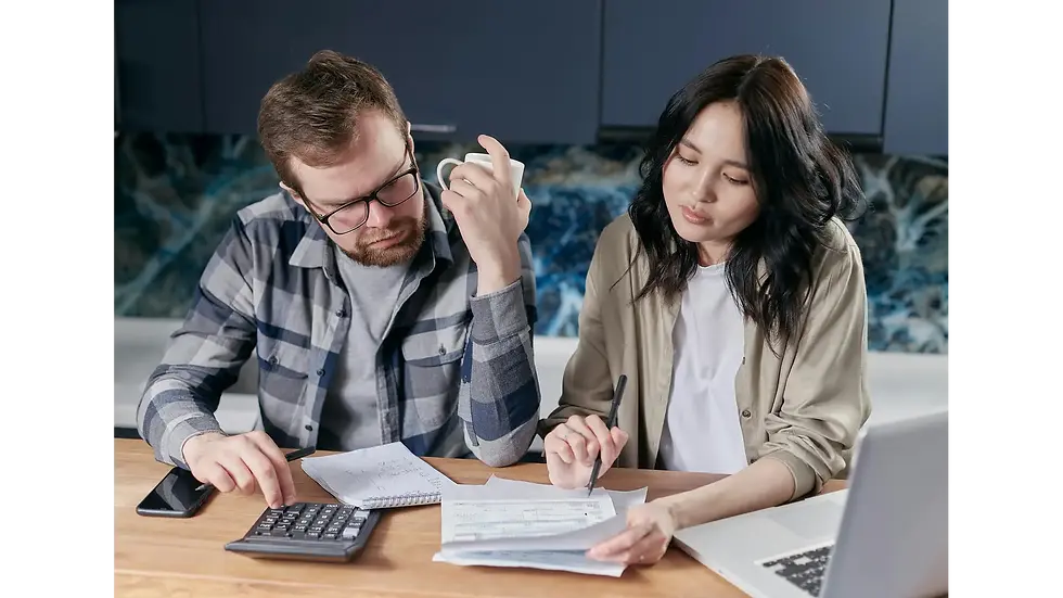 A couple reviewing bills and using a calculator at home to avoid budgeting mistakes