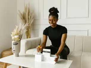 Smiling woman who knows how to organize her busy life using a desk organizer and colorful pens on a coffee table.