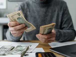 Person counting cash and learning how families stick with plans to manage a budget at the home desk