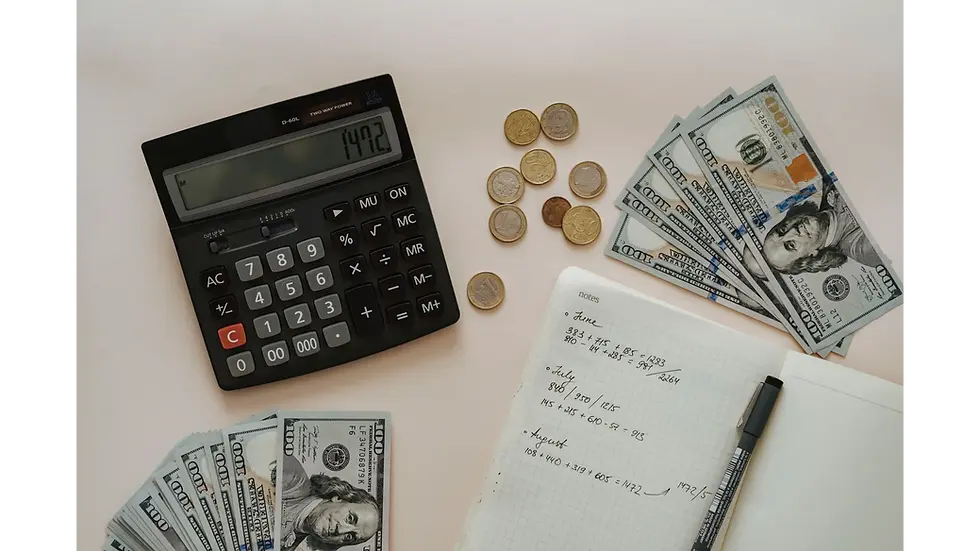 A person budgeting cash and coins for an emergency fund, using a calculator and notebook to track monthly expenses.