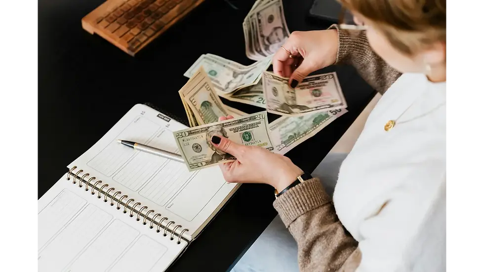 A person counting cash over a desk with a notebook, figuring out how to cut down and budget monthly expenses.