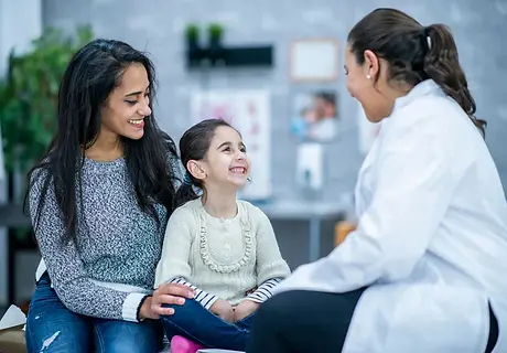 Smiling child with parent and pediatric provider during visit