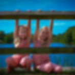 Two smiling girls behind a fence for a photography session.