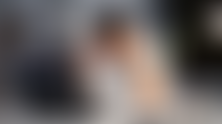 Man in white shirt holds head in frustration at desk with laptop. Papers and pen holder nearby. Office setting, muted colors, tense mood.