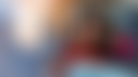 Woman in bed with red pajamas looks at phone, hand on head, appearing unwell. Nearby, nightstand with lamp, clock, and medicine.