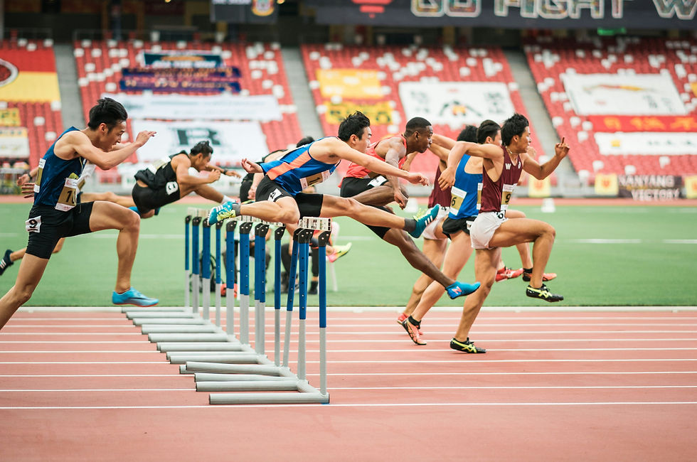 Athletes compete fiercely in a hurdle race, showcasing their agility and determination as they soar over the obstacles on a stadium track.