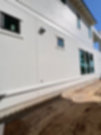 Smooth white stucco exterior with window trim and architectural bands on a custom home