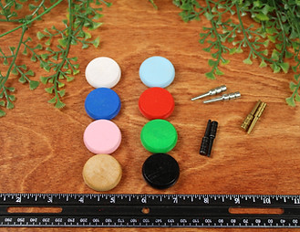 Several loose game pieces sitting on a table in front of a ruler with a plant in the background.