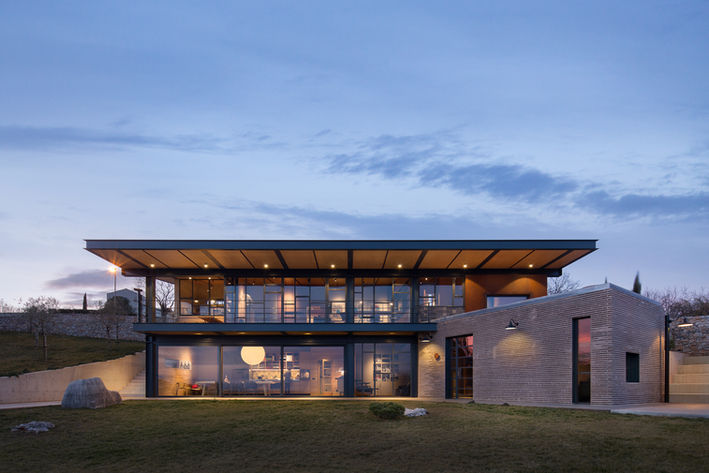 Modern brick house exterior at night with lights turned on.
