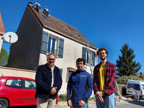 Deux employés de Zilo Energie se tiennent avec un client devant sa maison dont la toiture est en cours d'installation de panneaux photovoltaïques 