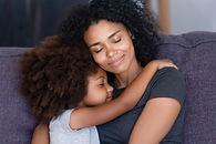 Close up biracial family portrait loving mother and little daughter sitting on couch at ho