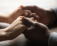 Mixed ethnicity family couple holding hands on table, black man friend husband support wom