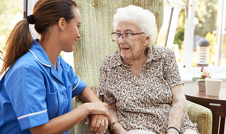 senior-woman-sitting-in-chair-and-talking-with-nur-49TDAYM-scaled.jpg