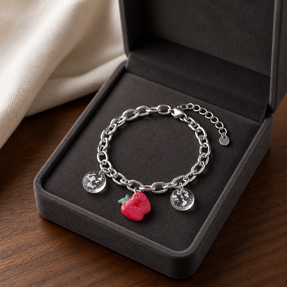Bracelet argenté à breloques avec pomme rouge en écrin.