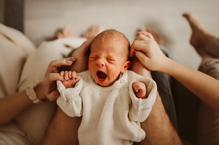 Ziewający noworodek na kolanach taty - sesja noworodkowa w domu Warszawa