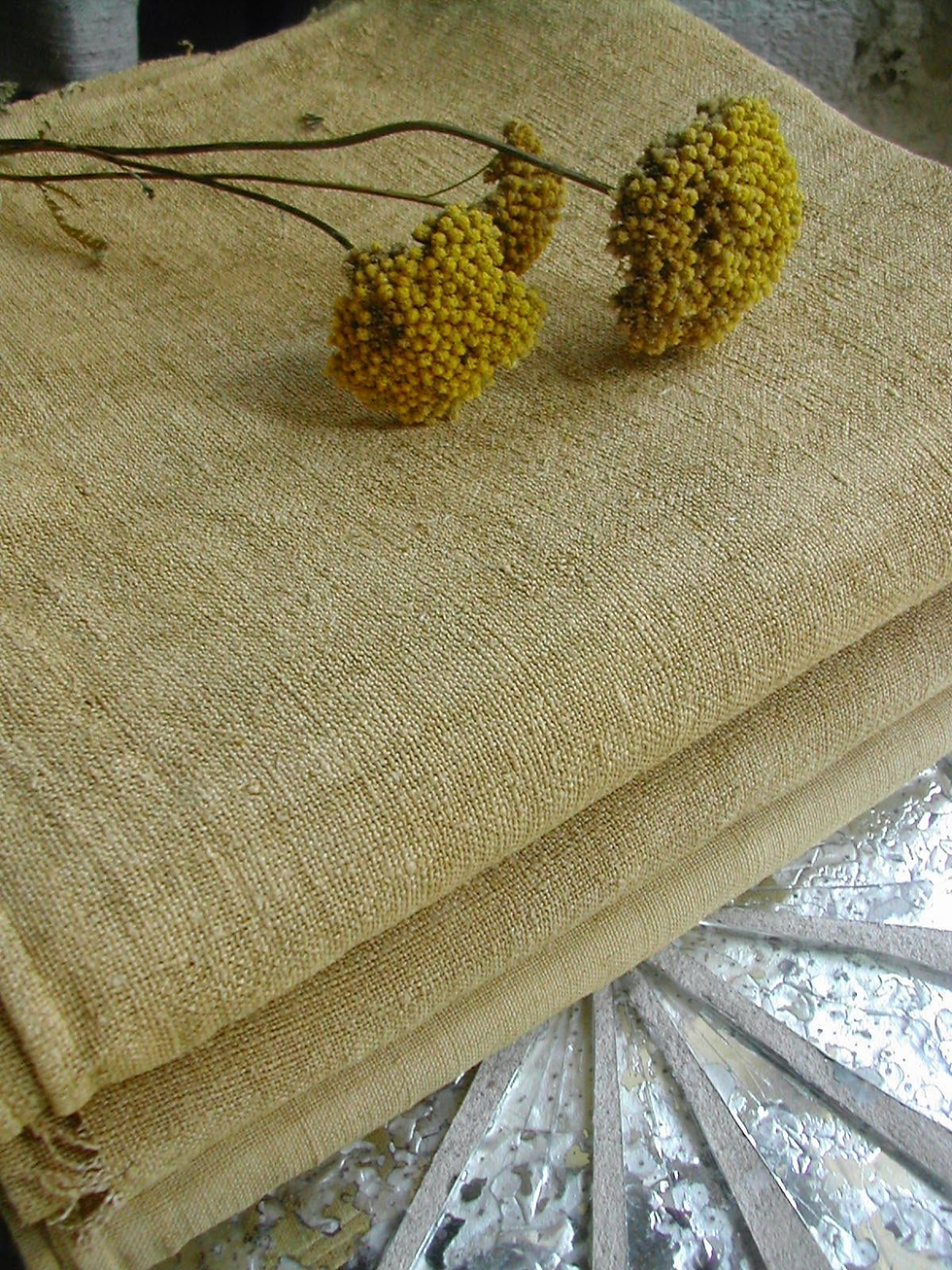 Yellow flowers on folded burlap cloth, set on a reflective metal surface. Natural tones create a rustic, calm ambience.