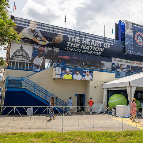 Main entrance of tennis event with oversized printed graphics, large tennis ball sculpture and signage
